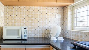 A kitchen with a microwave, a toaster, and a window with blinds. - Housr Benson Marathahalli Bangalore (Bengaluru)