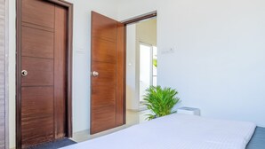 A bedroom with a bed, a wooden door, and a potted plant. - Housr Benson Marathahalli Bangalore (Bengaluru)