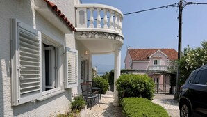 A house with a stone-paved patio, white shutters, and a balcony with white balustrades. - Apartment Zlatica - 530 m from sea, terrace, BBQ, private parking (Šilo)