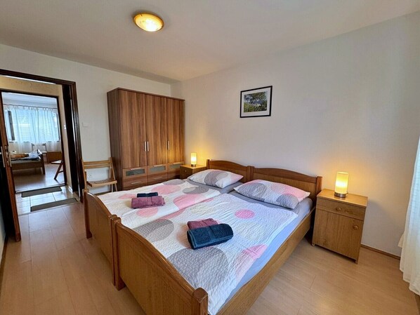 Un dormitorio con una cama de madera, mesitas de noche con lámparas, un armario y un cuadro en la pared.