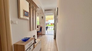 A hallway with a wooden cabinet, a mirror, and a framed picture on the wall. - Apartment Zlatica - 530 m from sea, private terrace, garden view, private parking, BBQ (Šilo)