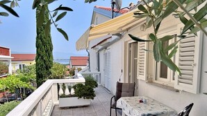 A balcony with a table and chairs, a potted plant, and a view of the sea. - Apartment Zlatica - 530 m from sea, private terrace, garden view, private parking, BBQ (Šilo)