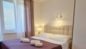 Ein Hotelzimmer mit einem großen Bett, einer Nachttischlampe und einem Fenster mit Vorhängen.
