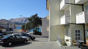 A building with a sign reading "AK ZARUL" and a view of mountains in the background. - Apartment Brnic AQ 3 - with Balcony, 90 m from the Beach (Baska)