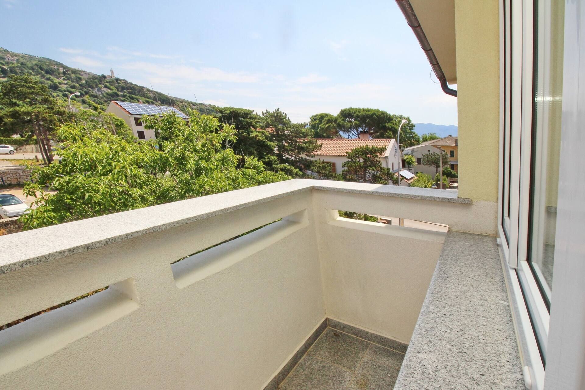 A balcony with a view of a residential area, including houses and greenery.