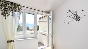 A bedroom with a bed, a window with curtains, a balcony, and a wall decal. - Apartment Dorcic AQ 1 - central Location, close to the Beach (Baska)