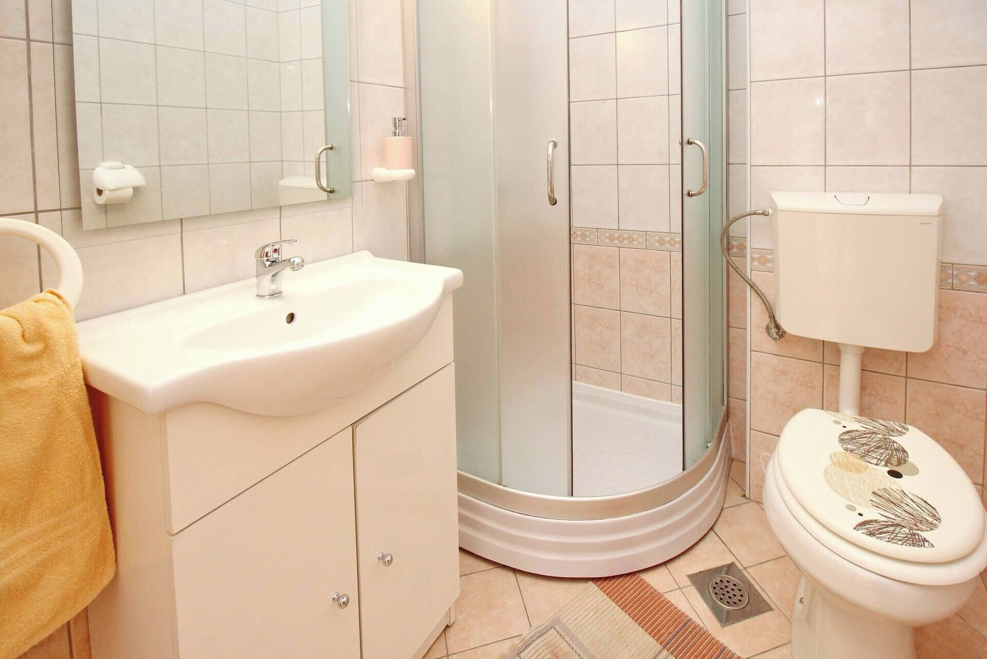 Une salle de bain équipée d’un lavabo, d’un miroir, de toilettes et d’une cabine de douche.