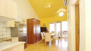 A compact kitchen with a refrigerator, wooden cabinets, and a dining area with a table and chairs.