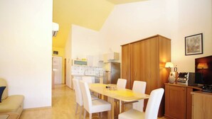 A compact living space with a dining area, kitchenette, and a TV setup.