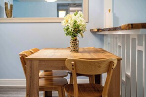 Una mesa de comedor de madera con un florero, rodeada de sillas de madera.