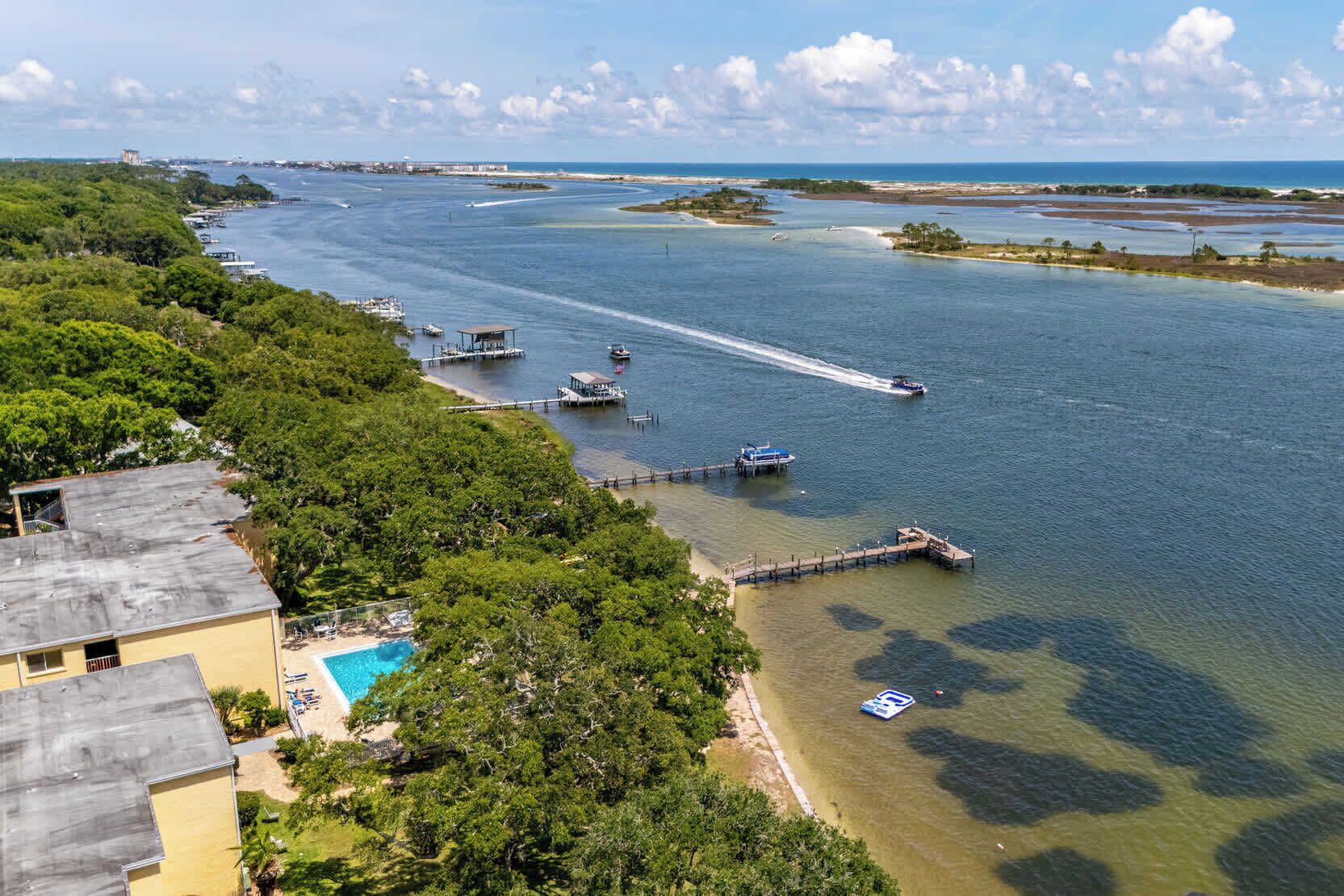 A coastal area with a clear view of the water, docks, and a swimming pool.