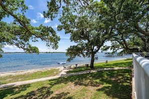 A lakeside view with a dock, a boat, and a grassy area with a bench.