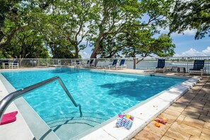 A swimming pool with clear blue water, surrounded by lounge chairs and a white fence. - ‼️Calm Waterside Condo‼️ | Kayaks, Paddles, Pool (Mary Esther)