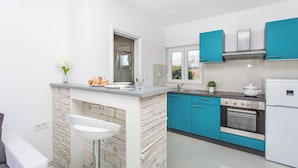 Une cuisine moderne avec un mur d’accent en pierre, un évier encastré et une cuisinière.