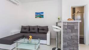 Ein modernes Wohnzimmer mit einer Eckcouch, einem Glastisch und einer Wand mit Steinverkleidung.