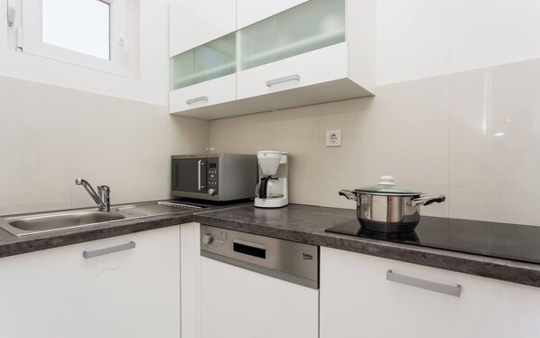 Una cocina moderna con lavavajillas integrado, cafetera y una olla sobre la encimera.