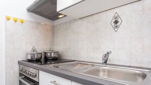 A modern kitchen with a stainless steel sink, a built-in oven, and a black countertop.