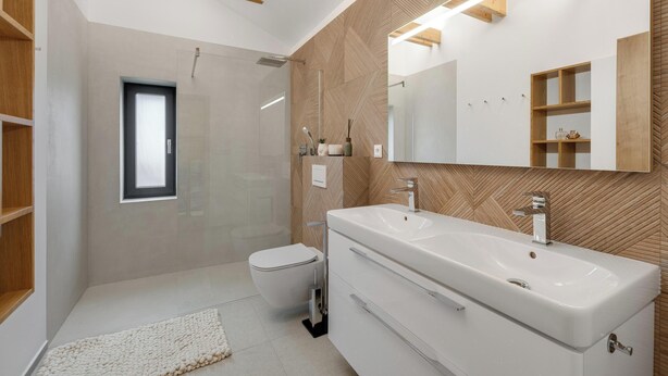 Un baño moderno con un lavamanos grande, un inodoro y una ducha.