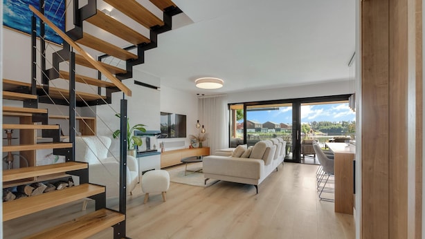 Una sala de estar moderna con una escalera, un sofá y un comedor.