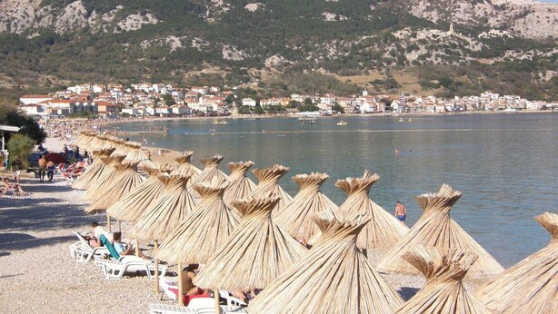 A beach with straw umbrellas and white lounge chairs. - Charming Apartment Brnic No. 4 - with spacious Balcony (Baska)