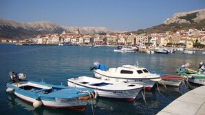 A marina with several boats docked, a town in the background, and mountains. - Charming Apartment Brnic No. 8 - with Balcony (Baska)