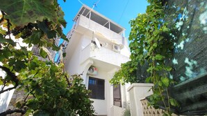 A two-story building with a balcony, satellite dish, and a door with shutters. - Apartment Bugi PRIZ - on the Ground Floor, with Terrace (Baska)