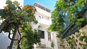 Um edifício residencial com fachada branca, janela visível e varanda.