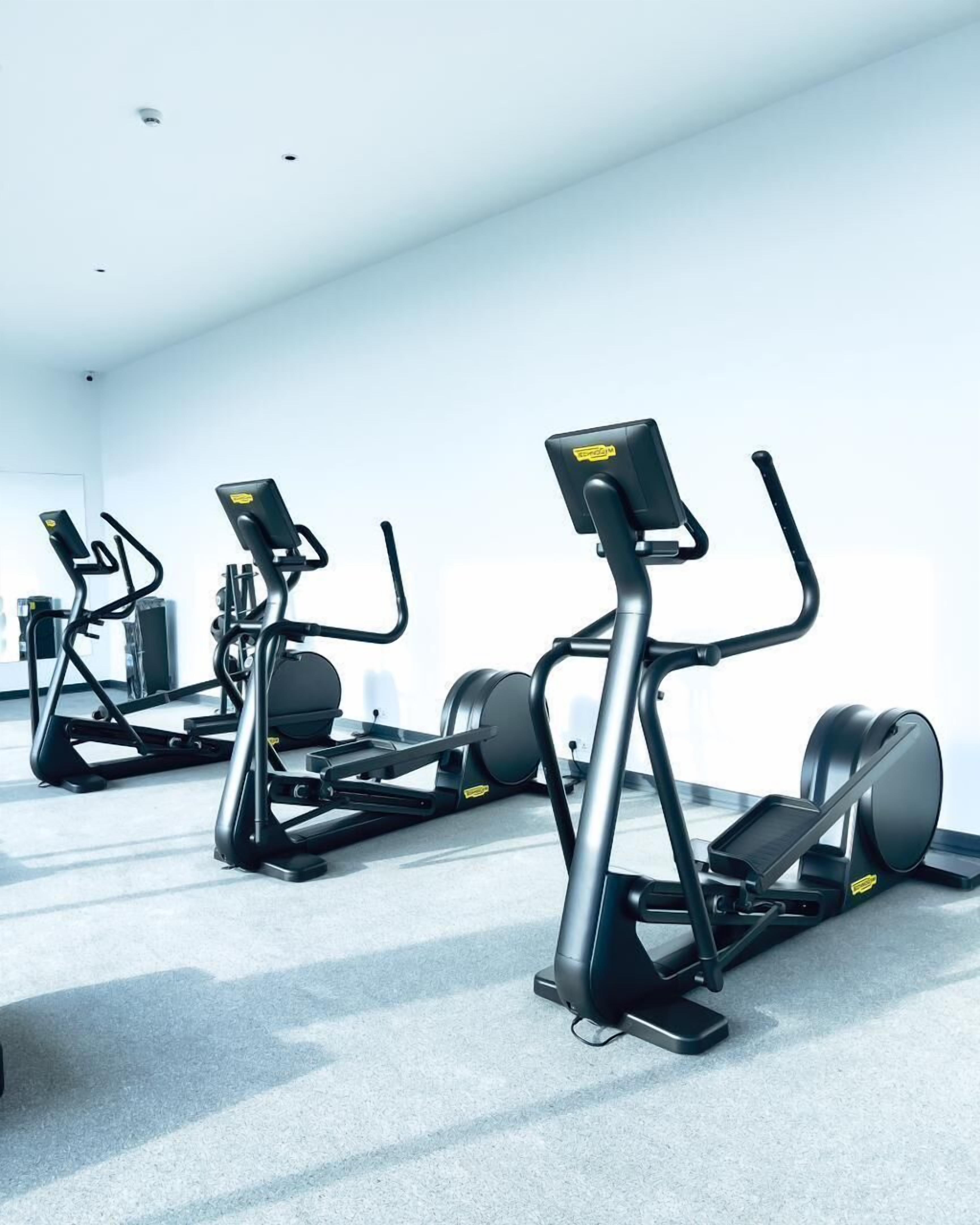 Une salle de sport équipée de plusieurs appareils elliptiques disposés en rangée.