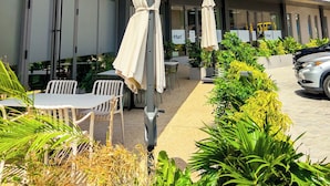 A modern hotel with outdoor seating and a visible 'C'Mart sign. - Meraki Homes at Loxwood House (Accra)
