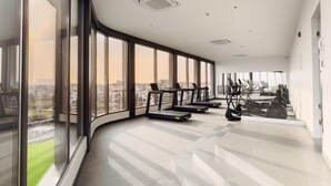 A spacious indoor area with large windows, a curved ceiling, and exercise equipment. - Meraki Homes at Loxwood House (Accra)