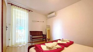 A hotel room with a bed, a bench, a mirror, and an air conditioning unit. - Capic Z3 - Apartment with Balcony and Parking spot, 300 m from the Beach (Baska)