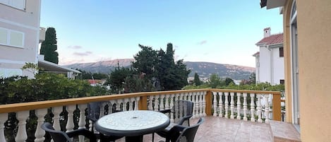 A balcony with a round table and four chairs, overlooking a mountainous landscape.