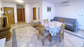Ein Essbereich mit Tisch und Stühlen, einer Couch und einem Fernseher.