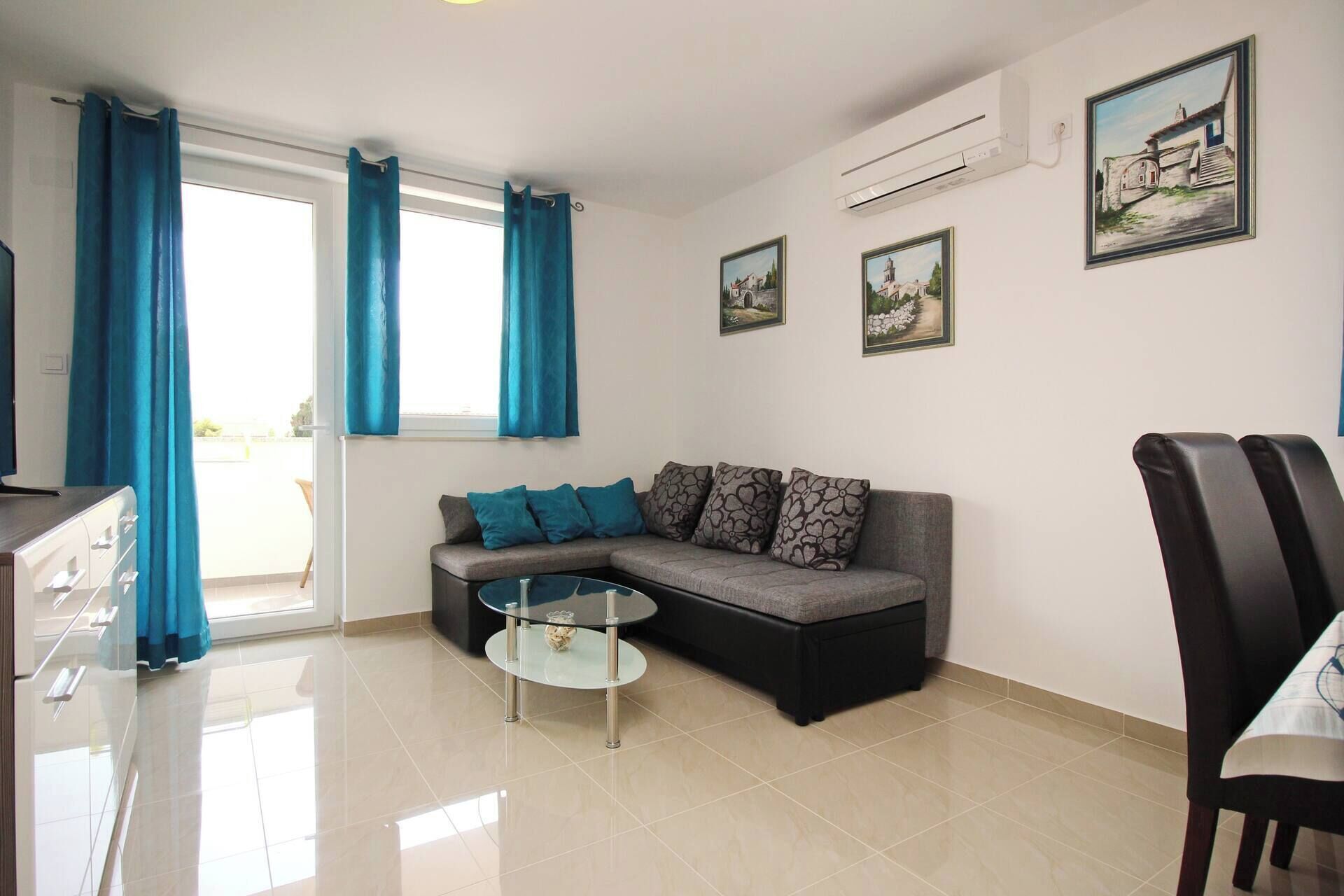 A modern living room with a sofa, a glass coffee table, and a dining area with a chair.
