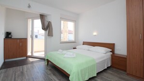 A bedroom with a bed, a wardrobe, a desk with a coffee maker, and a window. - Room Dekanic No.3 - with mini Fridge and Balcony (Baska)