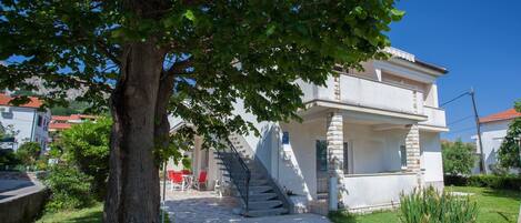 A two-story house with a stone staircase leading to the entrance.