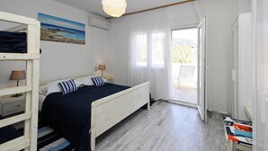 A bedroom with a bed, a hanging light fixture, a painting, and a view through a window. - Apartment Fantov No.3 - with large Balcony, 250 m from the Beach (Baska)