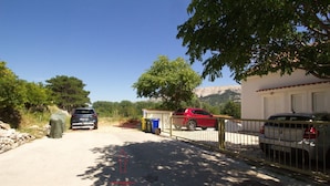 A parking area with covered cars, a building with a white facade, and a mountainous backdrop.