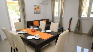 Een eetgedeelte met een tafel voor vier personen, omringd door stoelen, een bank en een decoratieve vaas.