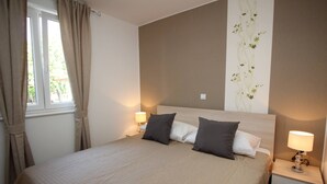Ein ordentlich eingerichtetes Hotelzimmer mit einem großen Bett, zwei Nachttischen mit Lampen und einem Fenster mit Vorhängen.