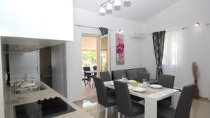 Een moderne keuken met een ingebouwde kookplaat, een eethoek met een tafel en stoelen, en uitzicht op de omgeving.