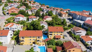 Ein Küstenwohngebiet mit Häusern, einem Schwimmbad und Blick aufs Meer.