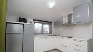 Eine moderne Küche mit weißen Schränken, einem Edelstahlkühlschrank, einer Mikrowelle und einem Fenster, das für natürliches Licht sorgt.