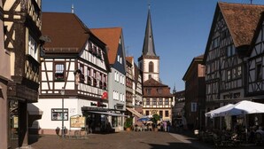 A traditional European street with half-timbered buildings, a church spire, and outdoor seating areas. - CORONA and flooding - SAFE due to location and separate entrance (Marktheidenfeld)