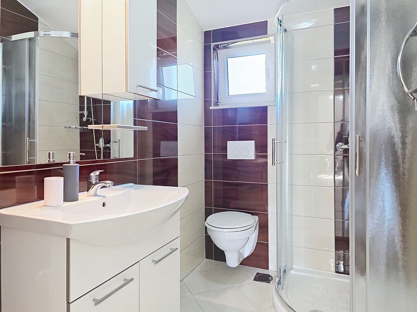 Een moderne badkamer met een wastafel, spiegel, toilet en douche.