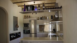 Una cocina moderna con electrodomésticos de acero inoxidable, un botellero y taburetes de bar.