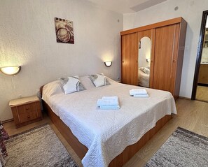 Un dormitorio con cama, armario, mesita de noche y lámpara de pared.