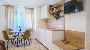 Eine moderne Küche mit Essbereich, einem an der Wand montierten Fernseher und einer Pflanze auf dem Regal.