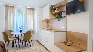 A modern kitchen with a dining area, a TV mounted on the wall, and a plant on the shelf. - Apartment Grozdana No.3 - with Balcony (Baska)