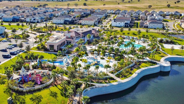 A residential area with houses, a swimming pool, and a playground. - 9BR Solara Resort Near Disney | Pool, Spa & Games (Kissimmee)